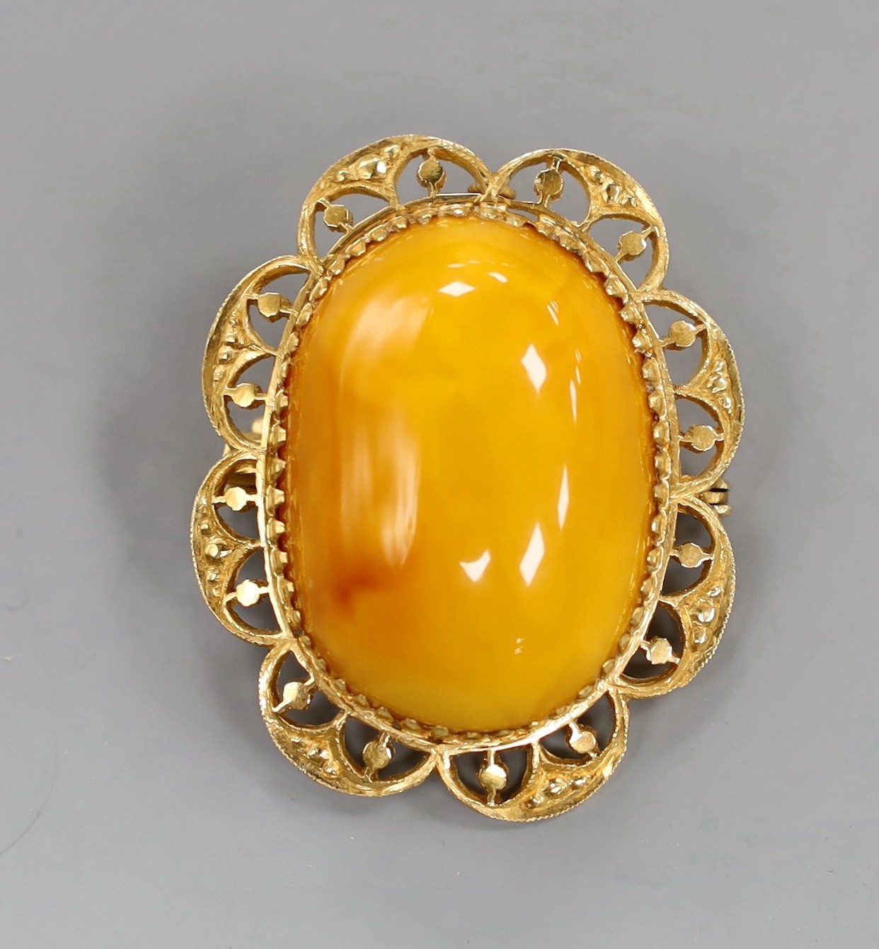 A 22ct mounted oval amber set brooch, 44mm, gross weight 12.1 grams.